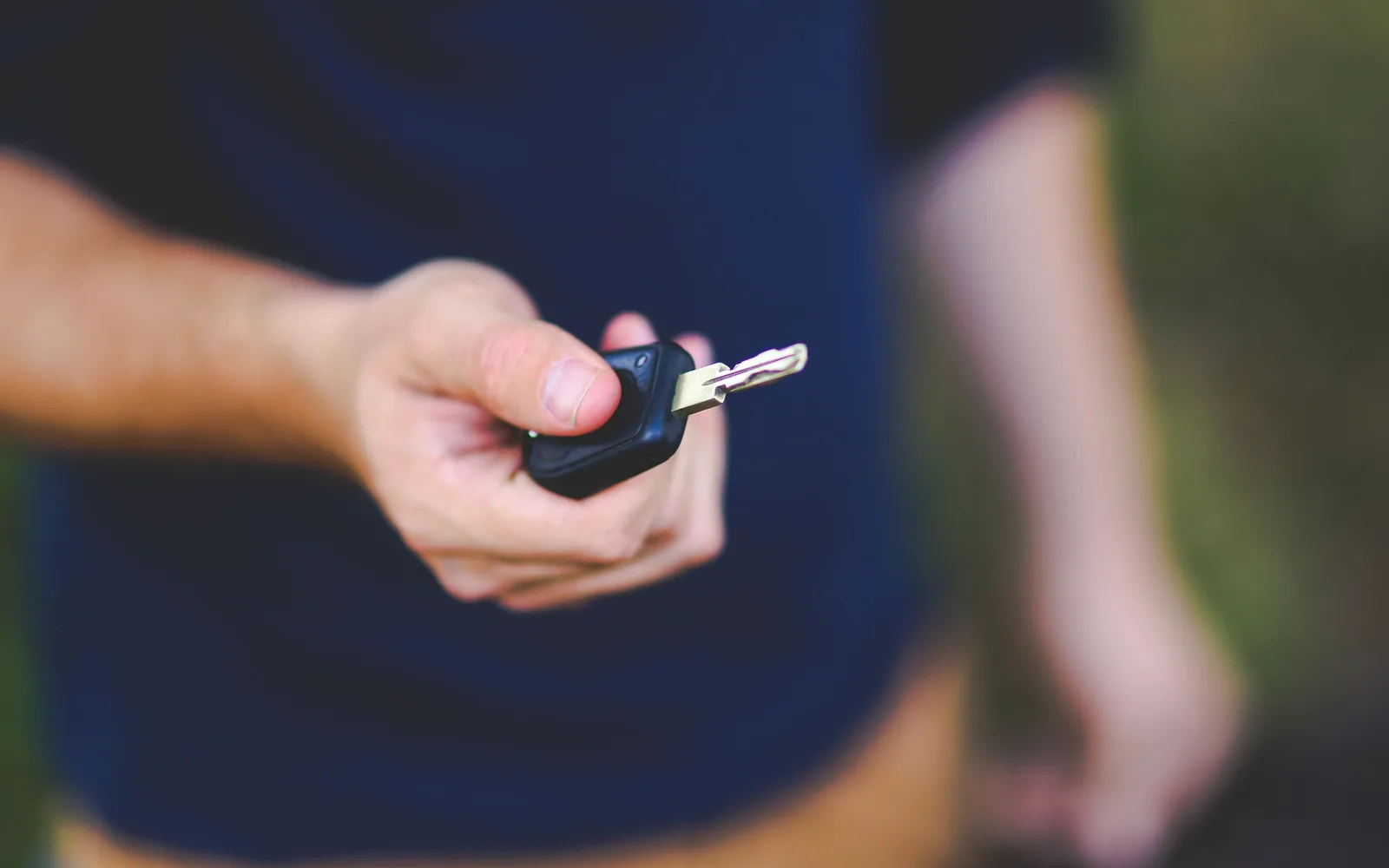 Main tenant une clé de voiture près d’une portière